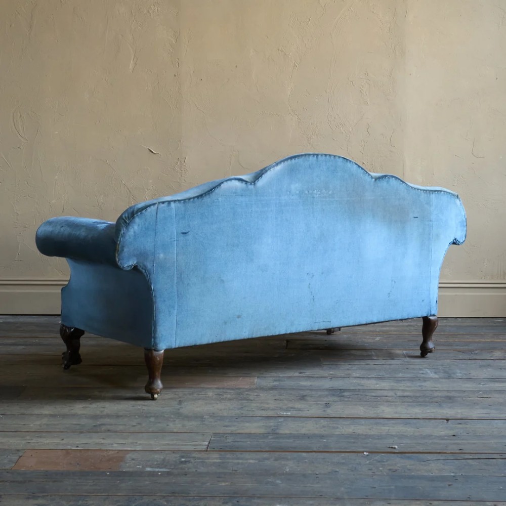 An antique blue velvet upholstered sofa featuring a curved back, rolled arms, and carved dark wooden cabriole legs with ball and claw feet on castors. View V