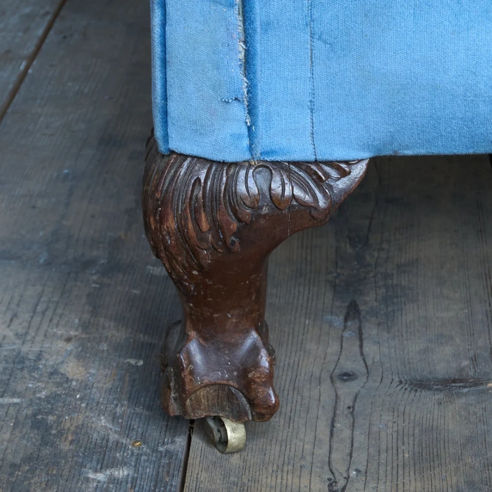 An antique blue velvet upholstered sofa featuring a curved back, rolled arms, and carved dark wooden cabriole legs with ball and claw feet on castors. View VI