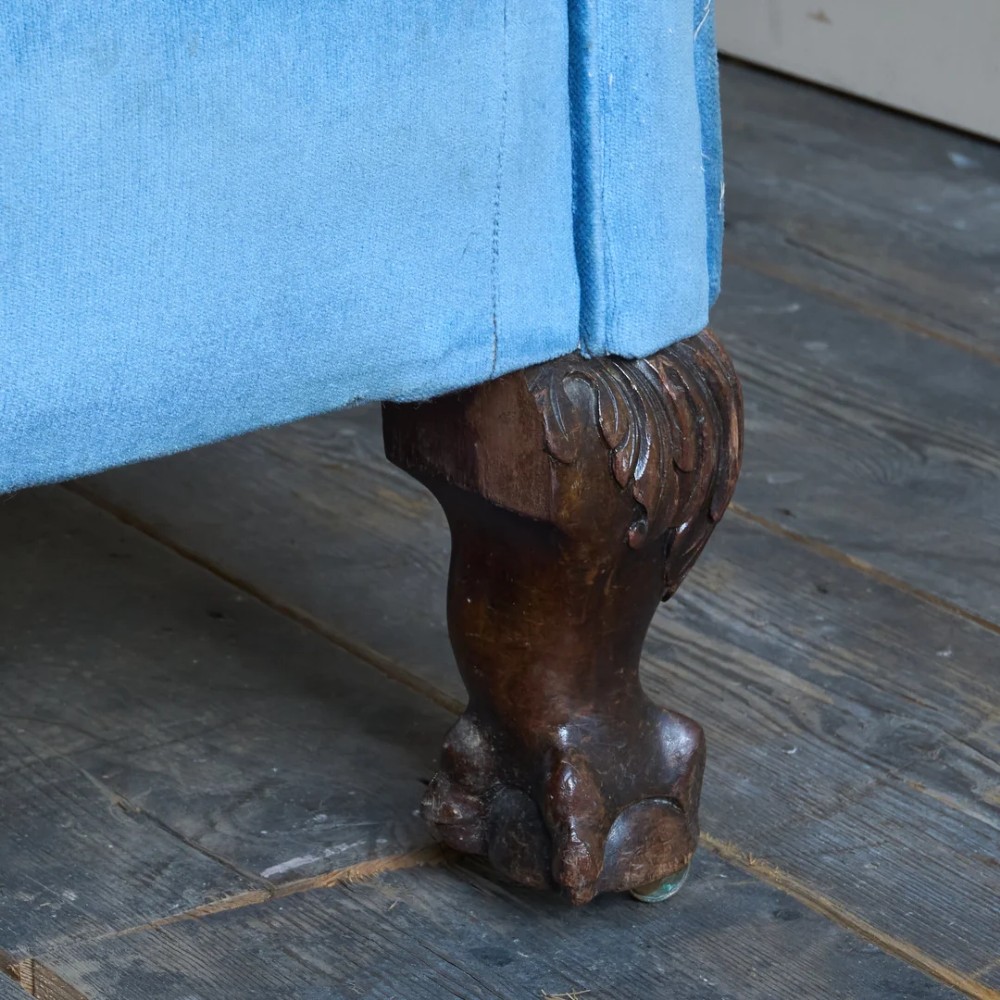 An antique blue velvet upholstered sofa featuring a curved back, rolled arms, and carved dark wooden cabriole legs with ball and claw feet on castors. View VII