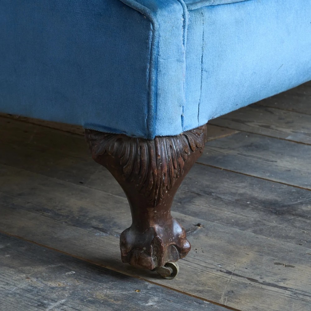 An antique blue velvet upholstered sofa featuring a curved back, rolled arms, and carved dark wooden cabriole legs with ball and claw feet on castors. View VIII
