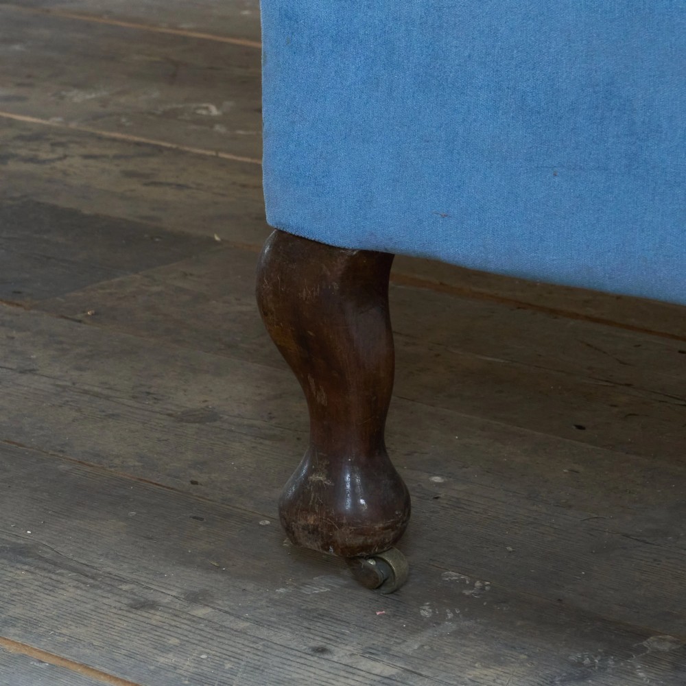 An antique blue velvet upholstered sofa featuring a curved back, rolled arms, and carved dark wooden cabriole legs with ball and claw feet on castors. View IX