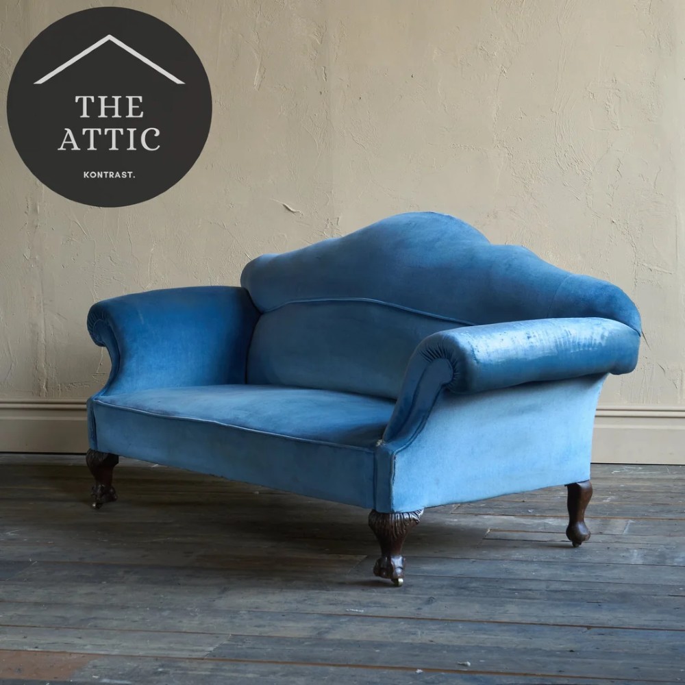 An antique blue velvet upholstered sofa featuring a curved back, rolled arms, and carved dark wooden cabriole legs with ball and claw feet on castors. View X