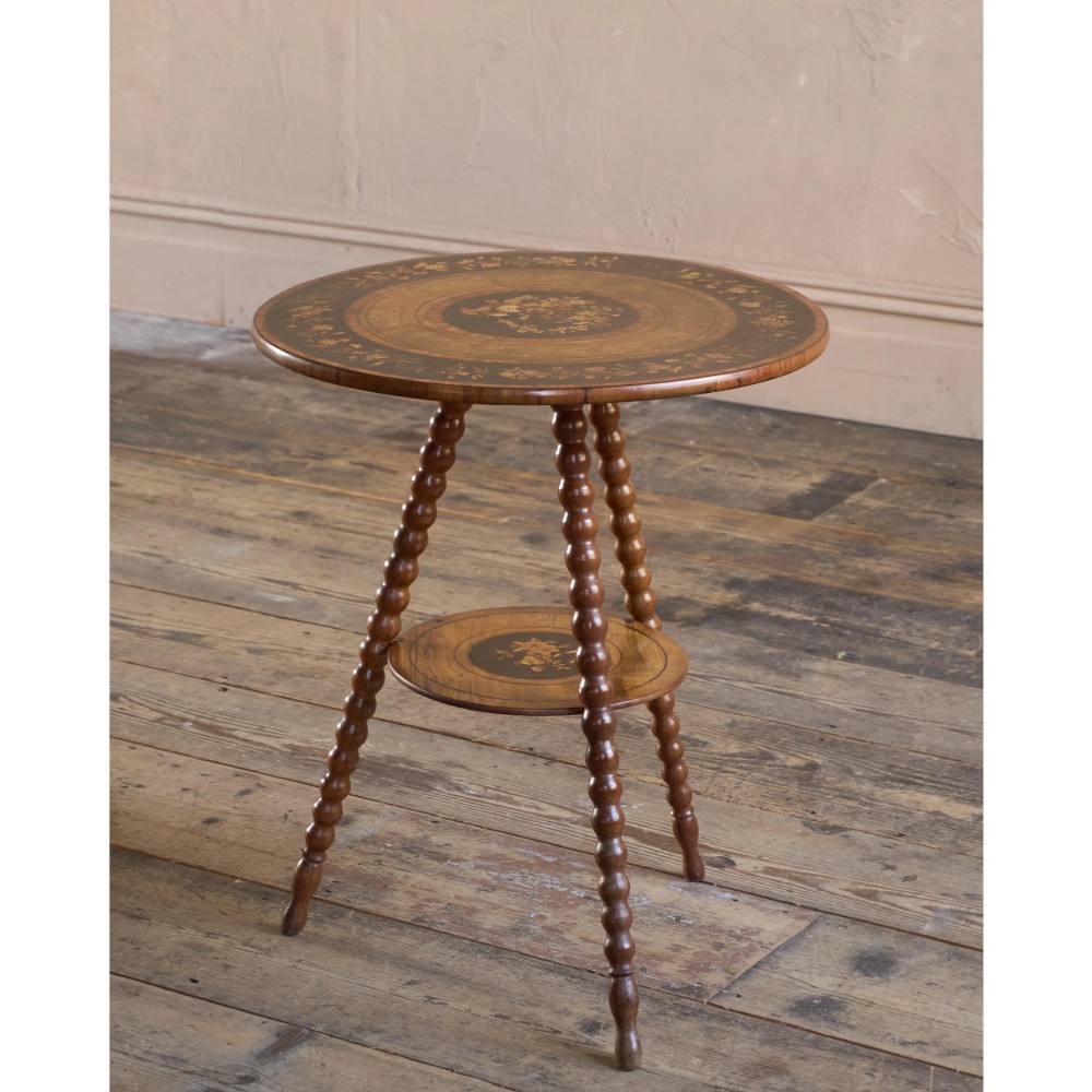 A circular warm brown wooden side table featuring floral marquetry inlays on the tabletop and lower shelf, supported by four bobbin-turned legs. View IV