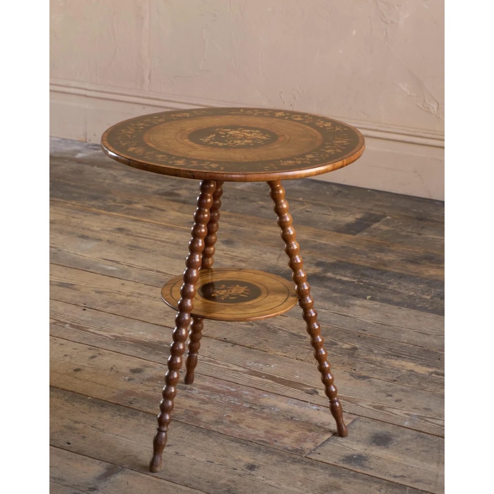 A circular warm brown wooden side table featuring floral marquetry inlays on the tabletop and lower shelf, supported by four bobbin-turned legs. View VII
