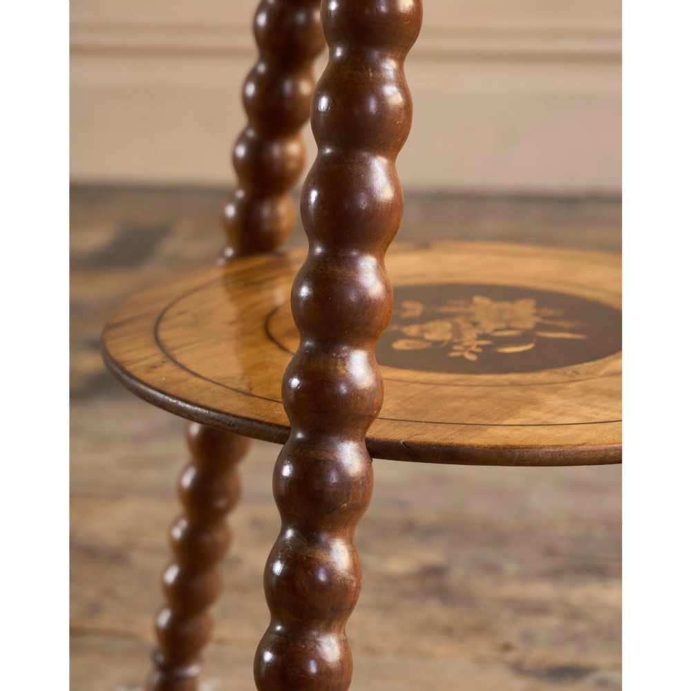 A circular warm brown wooden side table featuring floral marquetry inlays on the tabletop and lower shelf, supported by four bobbin-turned legs. View VIII