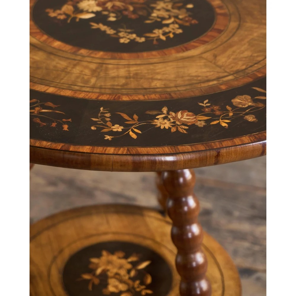 A circular warm brown wooden side table featuring floral marquetry inlays on the tabletop and lower shelf, supported by four bobbin-turned legs. View XI