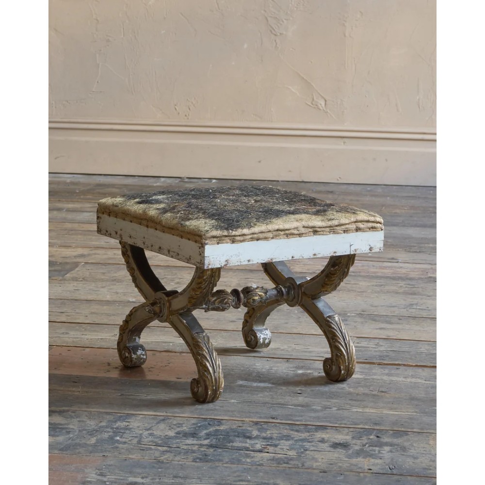 An antique curule X-frame footstool featuring carved scroll legs in grey paint and gilded finish with an upholstered top base. View VIII