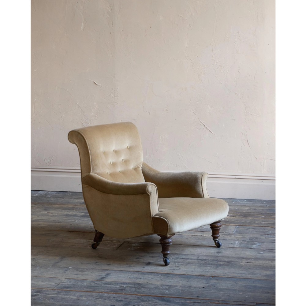 A Victorian button-back armchair upholstered in taupe velvet with turned front wooden legs set on metal castors. View II