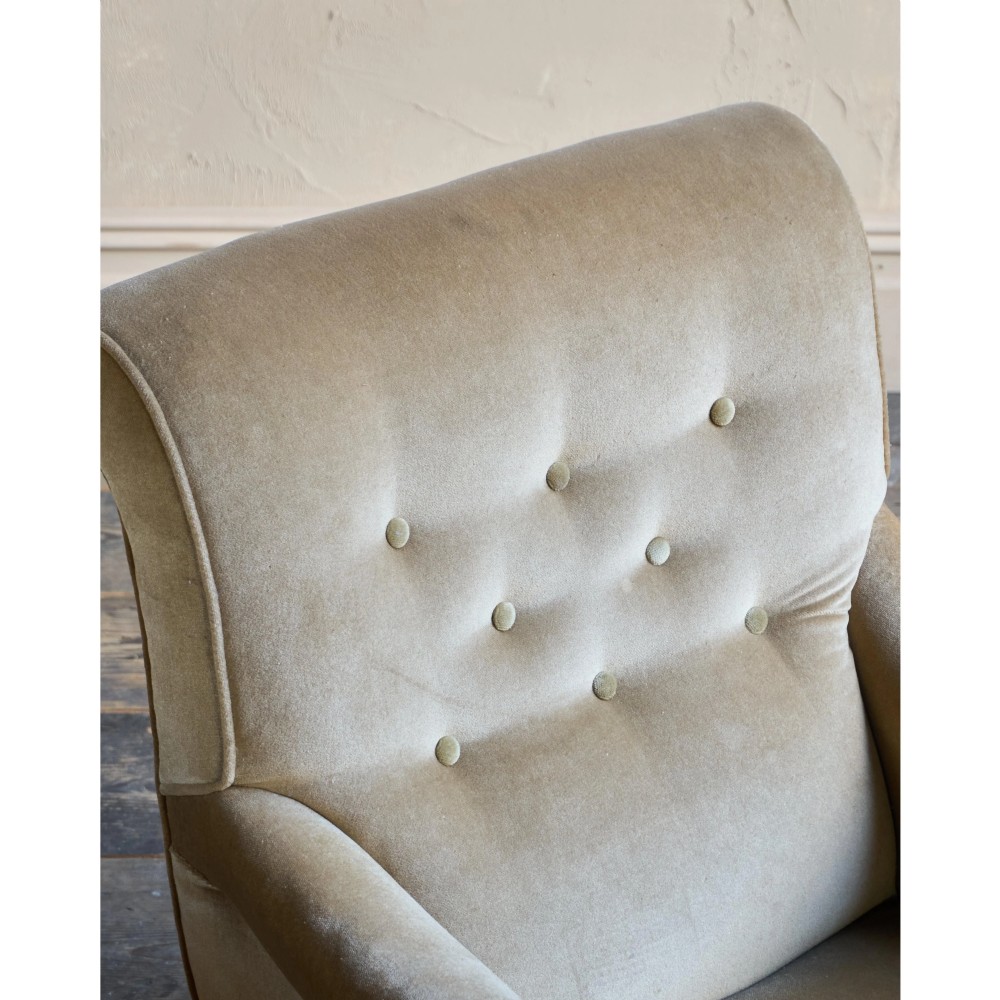 A Victorian button-back armchair upholstered in taupe velvet with turned front wooden legs set on metal castors. View V