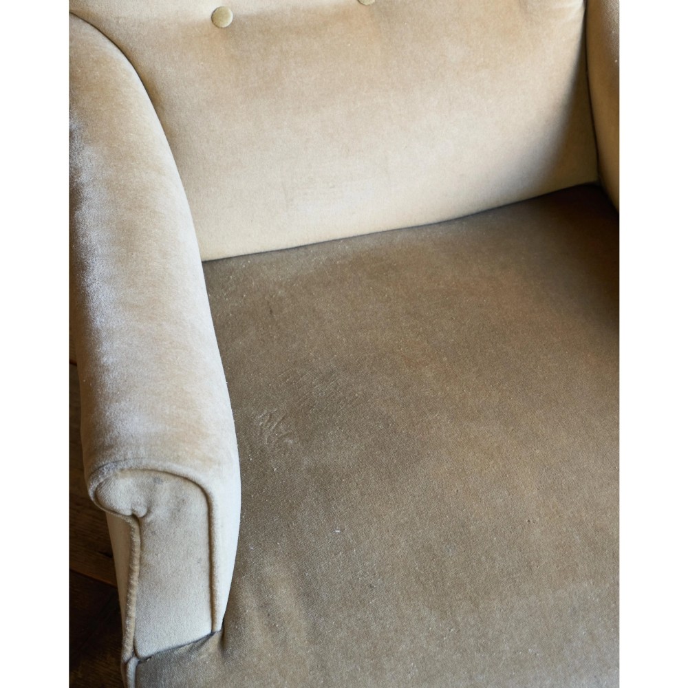 A Victorian button-back armchair upholstered in taupe velvet with turned front wooden legs set on metal castors. View VI