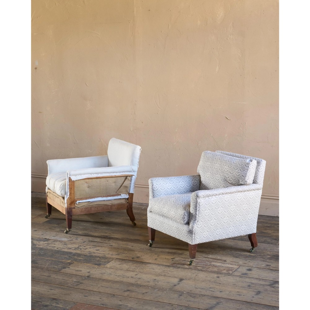 A pair of low-slung Victorian armchairs with turned wooden front legs and brass castors, one upholstered in patterned fabric and one in white calico. View IX