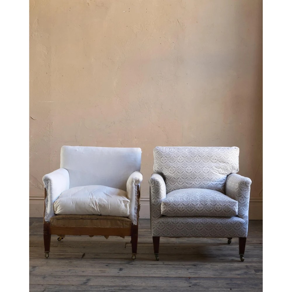 A pair of low-slung Victorian armchairs with turned wooden front legs and brass castors, one upholstered in patterned fabric and one in white calico. View XI