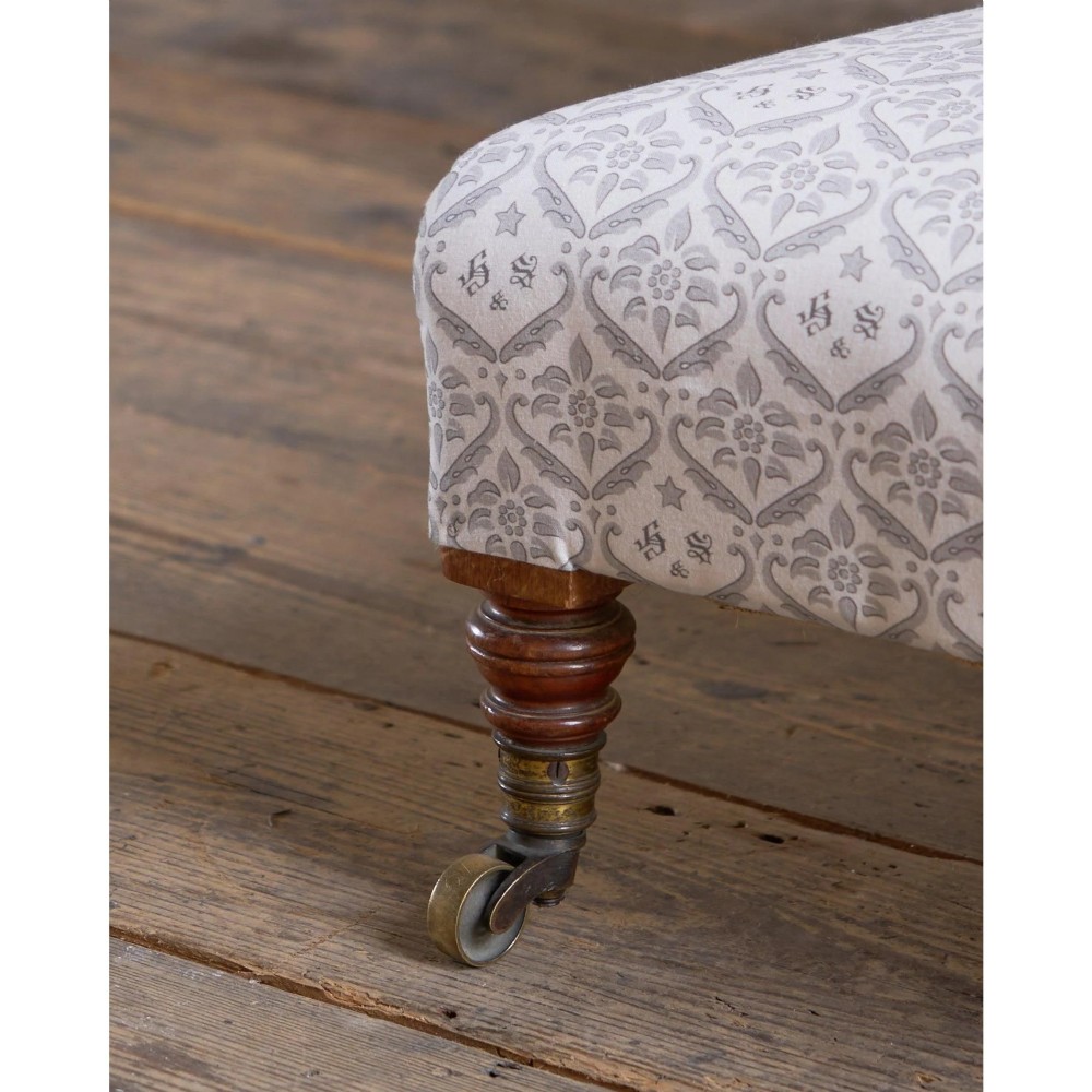 A low-seated Victorian armless slipper chair upholstered in grey patterned fabric with a button-back design and turned legs on brass castors. View VIII