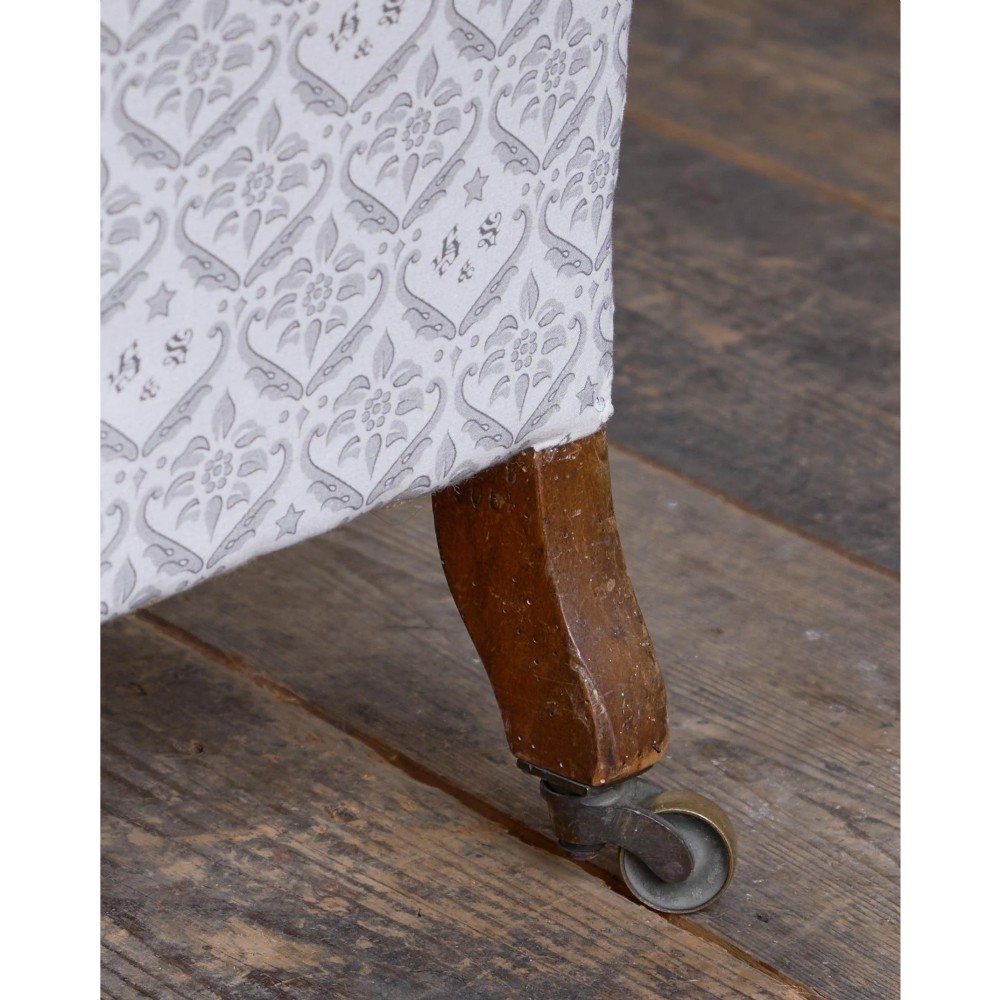 A low-seated Victorian armless slipper chair upholstered in grey patterned fabric with a button-back design and turned legs on brass castors. View IX