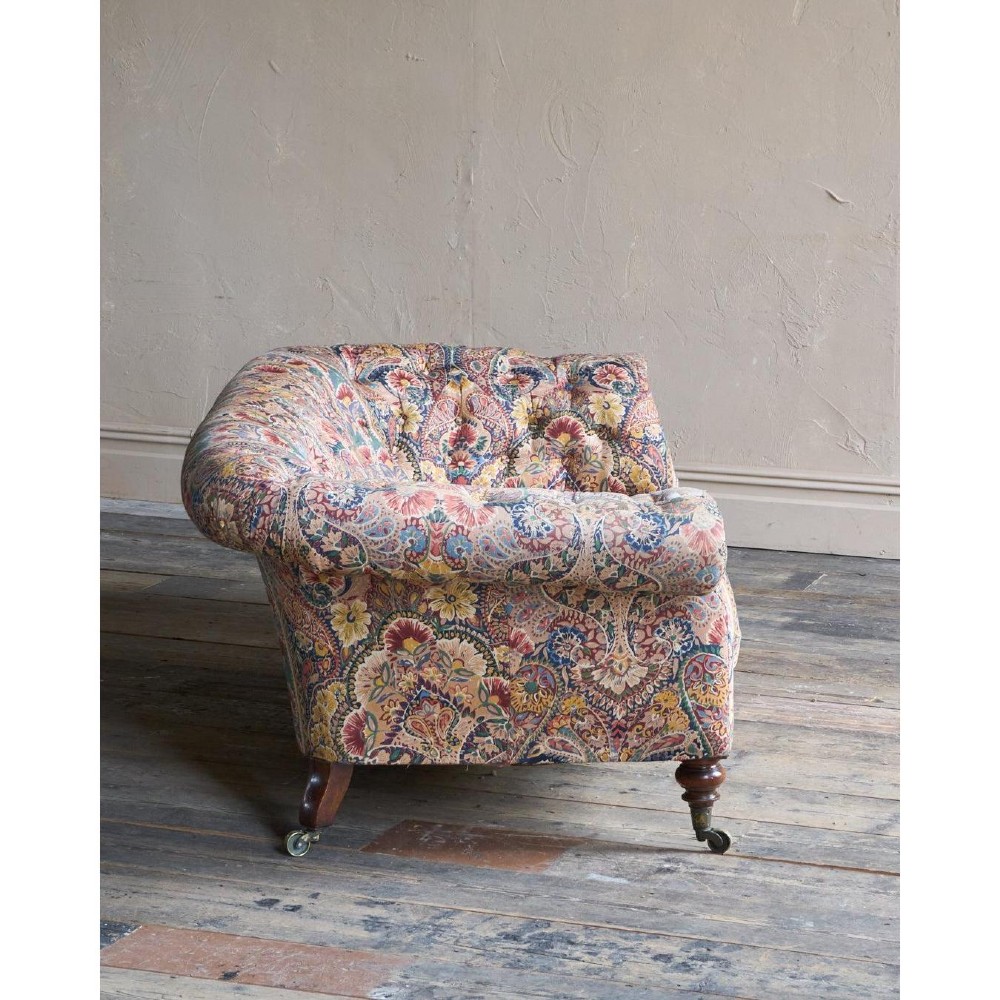 A Victorian Chesterfield sofa featuring deep-buttoned floral pattern upholstery, rolled arms, and turned wooden legs fitted with brass castors. View III