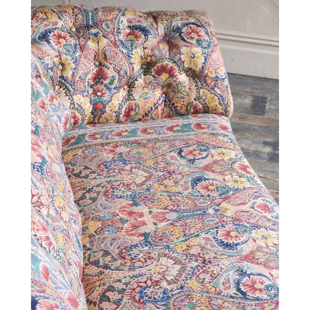 A Victorian Chesterfield sofa featuring deep-buttoned floral pattern upholstery, rolled arms, and turned wooden legs fitted with brass castors. View VI