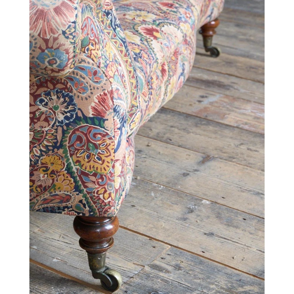 A Victorian Chesterfield sofa featuring deep-buttoned floral pattern upholstery, rolled arms, and turned wooden legs fitted with brass castors. View VIII