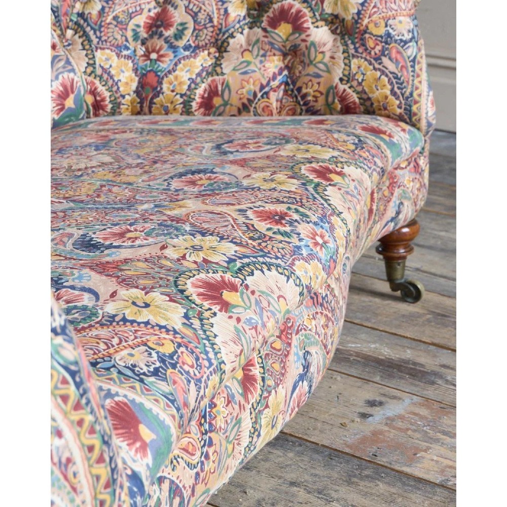 A Victorian Chesterfield sofa featuring deep-buttoned floral pattern upholstery, rolled arms, and turned wooden legs fitted with brass castors. View IX