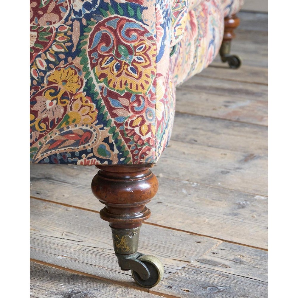 A Victorian Chesterfield sofa featuring deep-buttoned floral pattern upholstery, rolled arms, and turned wooden legs fitted with brass castors. View X