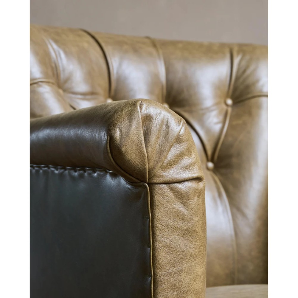 A deep-buttoned olive green leather armchair featuring turned wooden front legs with brass castors. View IX