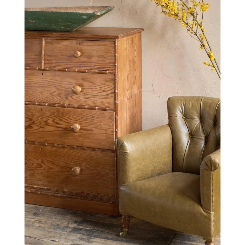 A deep-buttoned olive green leather armchair featuring turned wooden front legs with brass castors. View XIV