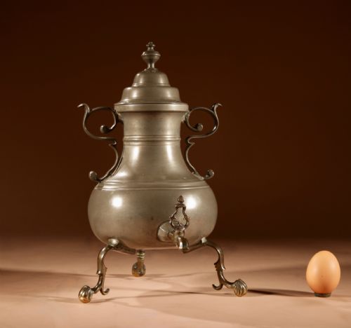 fig 1. An 18th-century Dutch pewter coffee urn featuring a bulbous body, brass spigot, twin handles, and tripod bronze legs.