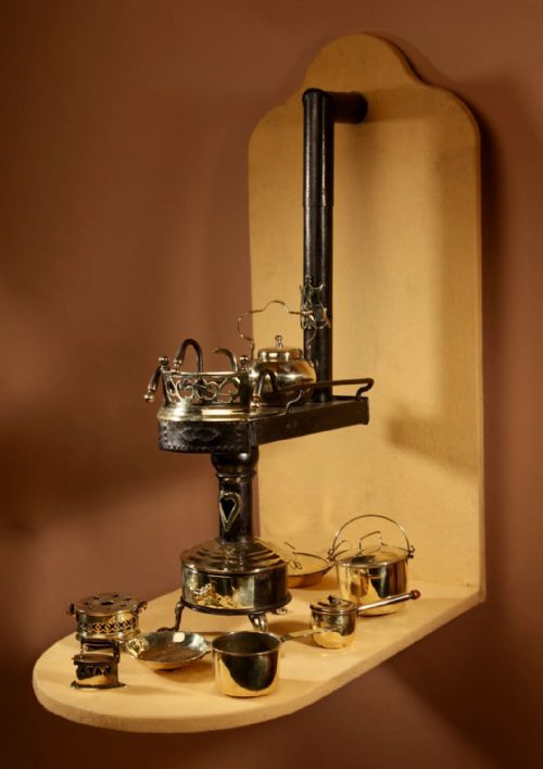 fig 1. A late nineteenth-century Continental miniature flat tub stove model crafted in black cast iron and brass, displayed with miniature brass pots, pans, and a kettle.