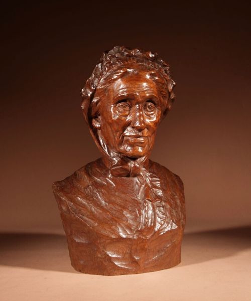 fig 1. A hand-carved brown wood bust depicting an elderly woman wearing a bonnet and tied neck scarf.