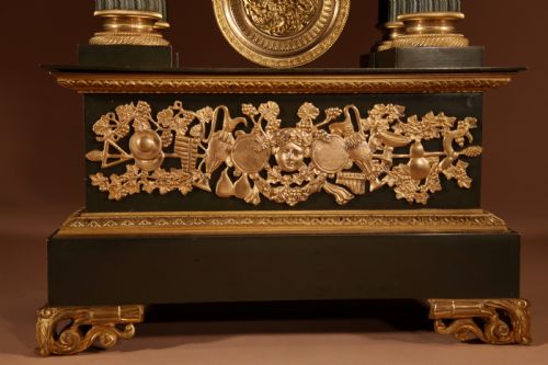 fig 2. A late nineteenth-century French portico clock featuring dark patinated bronze columns, decorative gilt bronze mounts, a white enamel dial with Roman numerals, and an ornate pendulum.
