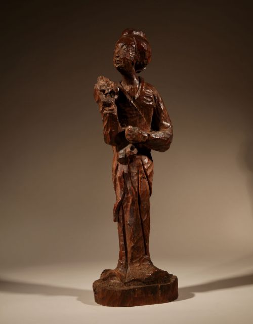 fig 1. A hand-carved dark wood sculpture of a standing geisha in the Japanese nata-tsukuri style with visible chisel facets.