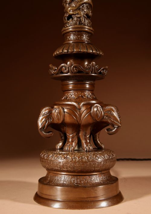 fig 1. A dark patinated bronze table lamp featuring cast elephant and dragon motifs topped with a pleated conical lampshade.