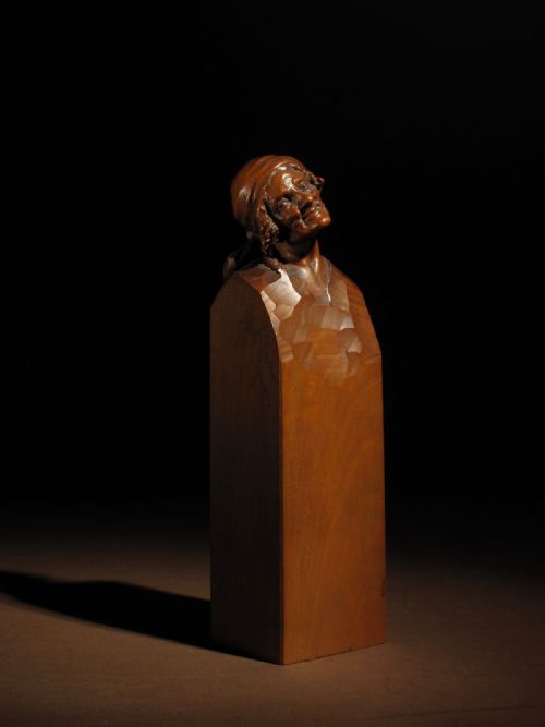 fig 1. Hand-carved pearwood sculpture of an elderly woman wearing a headscarf, emerging from an integral tall rectangular pedestal signed by Hermann Steiner Meran.