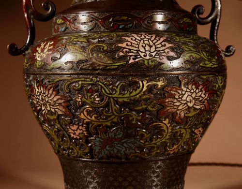 fig 1. A Japanese champleve bronze table lamp featuring floral enamel decoration, twin side handles, and a cream pleated shade.