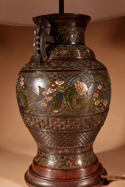 fig 1. An antique Japanese champleve bronze vase converted into a table lamp, featuring dragon motifs, twin handles, colourful enamel inlay, and topped with a pleated cream lampshade.