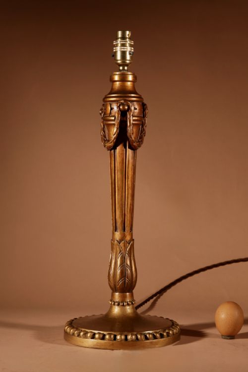 fig 1. A Louis XVI style carved giltwood table lamp featuring a fluted stem, beaded base, and cream pleated shade.