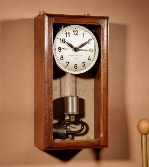 fig 1. An Art Deco electric master clock set inside a glazed oak case with a white circular dial and visible pendulum mechanism.