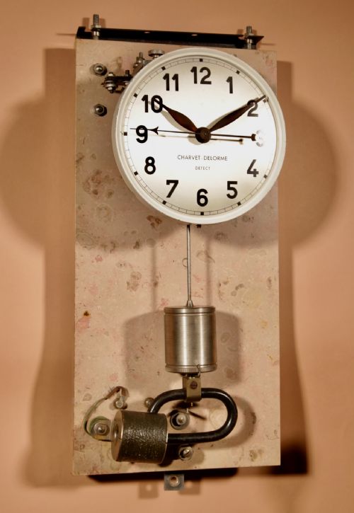 fig 2. An Art Deco electric master clock set inside a glazed oak case with a white circular dial and visible pendulum mechanism.