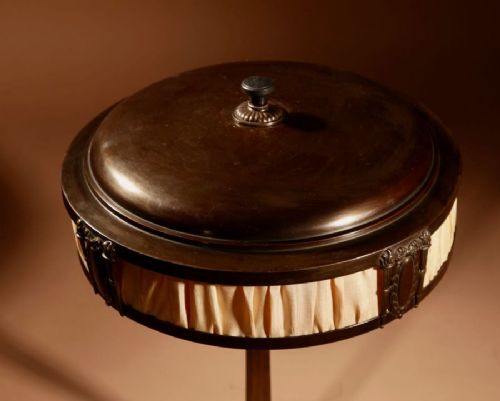 fig 1. An antique Jugendstil table lamp featuring a dark patinated metal base, a circular stem, and a domed shade emitting an amber glow through fabric inserts.