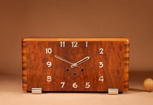 fig 1. A rectangular French Art Deco mantel clock crafted from figured walnut veneer featuring applied chrome numerals, geometric hands, and chrome bracket feet.