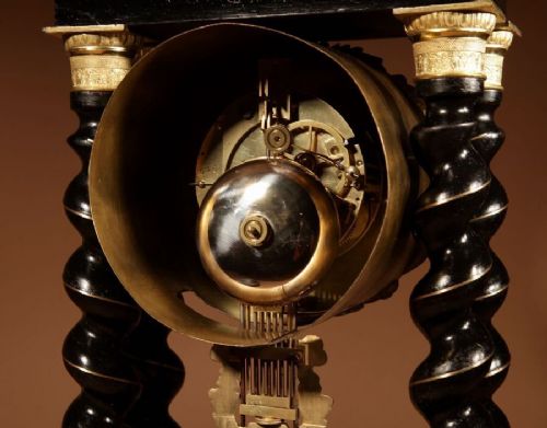 An ebonised French portico clock featuring brass stringing inlay, four barley-twist columns, an ornate gilt dial bezel, and an exposed ornate pendulum. View IV