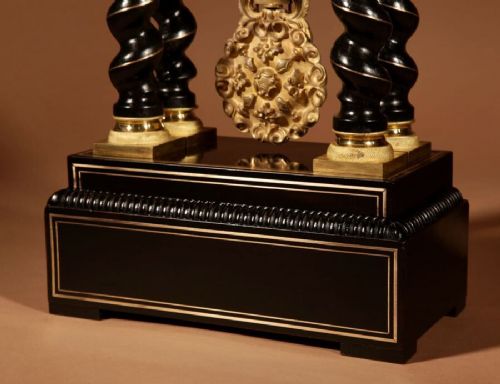 An ebonised French portico clock featuring brass stringing inlay, four barley-twist columns, an ornate gilt dial bezel, and an exposed ornate pendulum. View VII