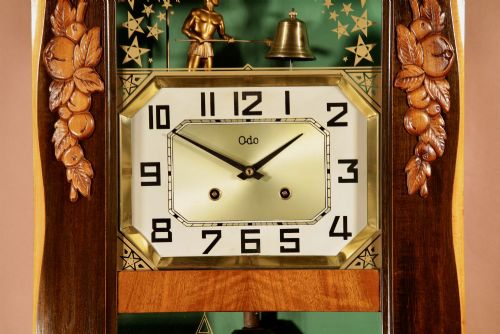 fig 2. An Art Deco carved walnut wall clock by Odo featuring a brass automaton bell striker and a Venetian glass lower window.