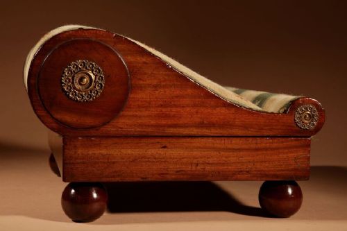 A 19th-century Continental mahogany sloped footstool featuring striped floral upholstery, brass side rosettes, and turned bun feet. View II