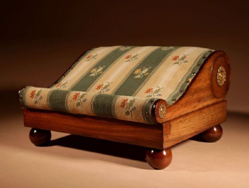 A 19th-century Continental mahogany sloped footstool featuring striped floral upholstery, brass side rosettes, and turned bun feet. View III