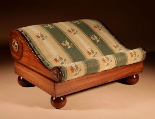 A 19th-century Continental mahogany sloped footstool featuring striped floral upholstery, brass side rosettes, and turned bun feet. View VI