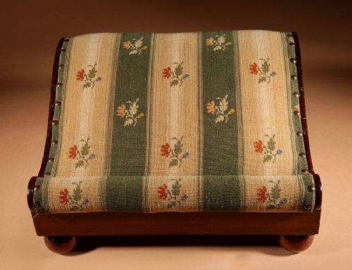 A 19th-century Continental mahogany sloped footstool featuring striped floral upholstery, brass side rosettes, and turned bun feet. View VII