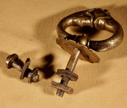 An 18th-century cast bronze door knocker featuring a stylized dolphin design suspended from a decorative floral rosette backplate. View VI