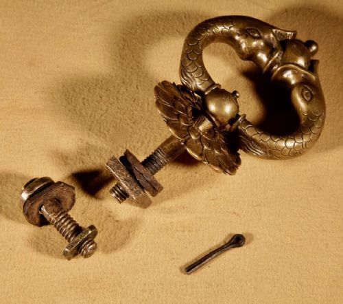 An 18th-century cast bronze door knocker featuring a stylized dolphin design suspended from a decorative floral rosette backplate. View VII