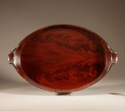 An oval mahogany serving tray featuring staved wood construction, twin carved side handles, and two horizontal brass bands securing the outer rim. View III