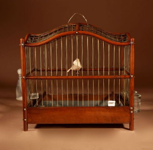 An Anglo-Dutch mahogany and brass birdcage featuring an arched wire dome roof, slide-out drawer tray, wooden perches, and accompanying glass vessels. View V